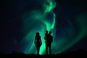 family silhouettes on the background of the northern lights