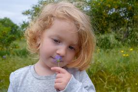 caucasian Baby Girl with Flower on meadow at summer