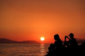 silhouette of people on the shore during sunset