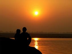 romantic couple by the river on a background of yellow sunset