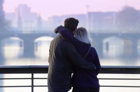 Back view of the couple, on the bridge with the beautiful city view, at purple sky on background