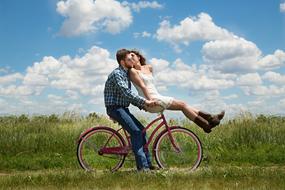 couple in love on a bicycle on a green field