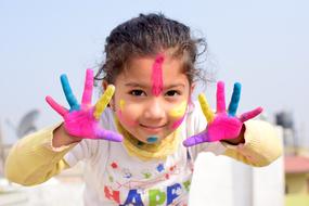 Child girl with Colorful painted hands and face