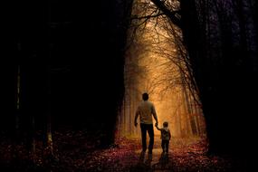 Father with son, walking on the beautiful and colorful path, among the trees at colorful sunset