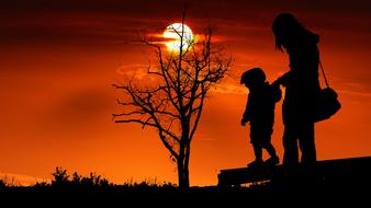 Child and Mother silhouette at Sunset sky