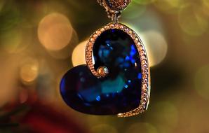 heart shaped pendant with blue stone close-up on blurred background