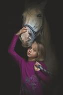 photo of a girl in a purple sweater with a white horse