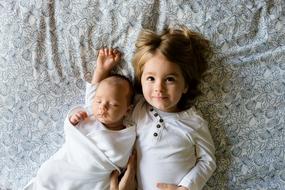 little girl lies with her newborn brother