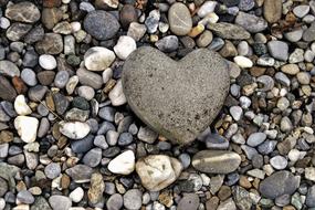 Beautiful stone in the shape of heart, among the colorful pebbles