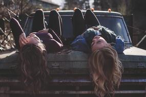 girls posing lying on a classic car