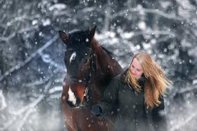 girl walks with a horse in snowfall