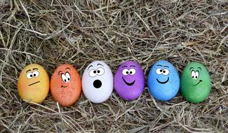 colorful easter eggs with faces on hay