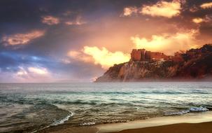 castle on a cliff near the sea at dusk