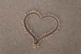 Beautiful heart drawing on the sandy beach in summer