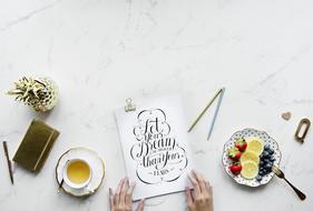 Person, at the workspace with the beautiful notebook of artist and food on the table