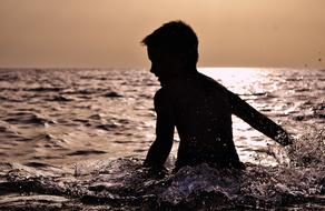 boy is splashing in the evening sea