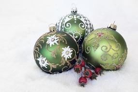 Beautiful, colorful and decorated Christmas baubles and red berries, on the white, soft surface