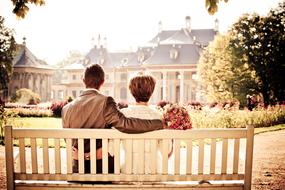 Couple resting on bench in front of palace