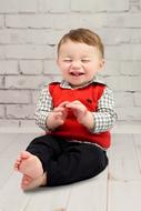 laughing little boy in a red vest