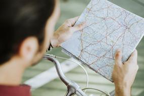 Active Adult caucasian man on bicycle with map