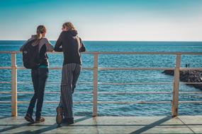 young caucasian Couple resting on pier at Seaside