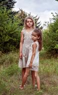 two sad child girls posing at summer forest