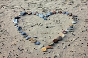 heart outline with colorful Stones on Sand Beach