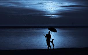 man and dog under umbrella in rain on waterside