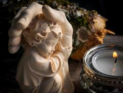 stone figure of an angel in a hand and a candlestick