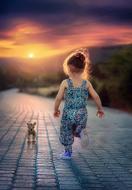 little girl walking the dog at sunset