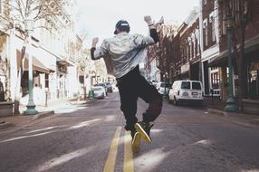 young man dancing on a dividing road marking