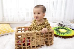 portrait of Boy kid in the basket and colorful pillows