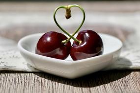 Two cherries in the white bowl as a symbol of love