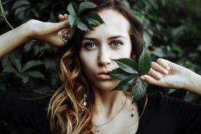 photo portrait of a girl among dark green leaves