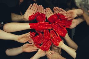 red paint on the palms of people in the shape of a heart