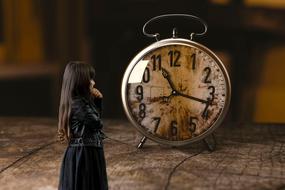 photo of a girl in a black dress on a background of an alarm clock