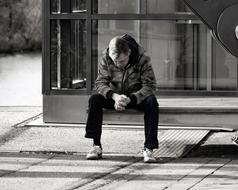 young man sits outdoor with bended head, Loneliness