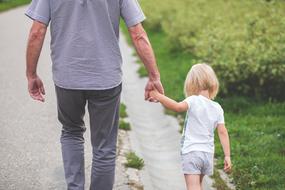 father and daughter are walking along a country road