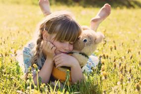 girl lying on the meadow with teddy