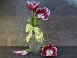 Beautiful, red, white and purple flowers in the glass vase with yellow and white ribbon with dots