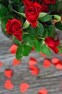 a bouquet of beautiful red roses and delicate red hearts with green leaves on the table