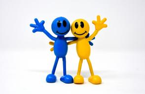 Two blue and yellow figures in friendship, at white background