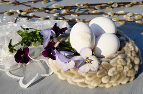 Beautiful, white Easter eggs, purple and white pansy flowers on the willow catkins