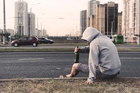 drunkard, male person with bottle sits on roadside in city, russia, moscow