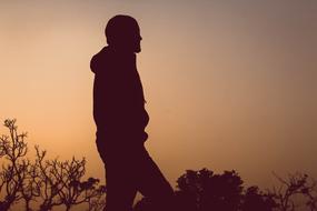 silhouette of walking man at sunset sky