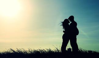 silhouette of a couple in love on the field against the blue sky