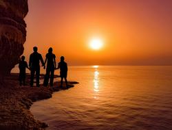 Silhouettes of the family, on the sea shore at beautiful and colorful sunset, in Cavo Greko, Cyprus, Greece