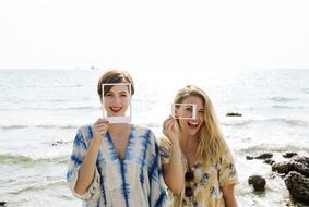 girls hold white frames in front of faces