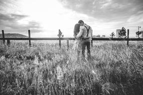 black and white photo of a kissing couple in a meadow