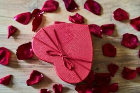 red heart-shaped box and rose petals on the table